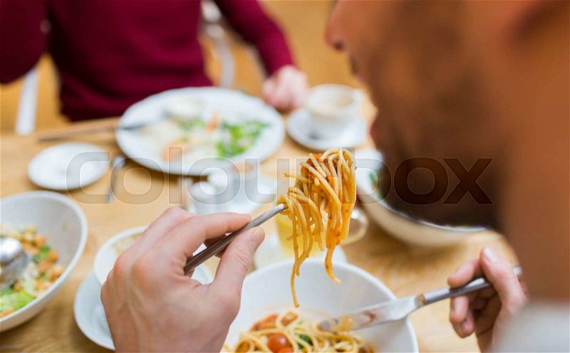 People, leisure and food concept - close up man eating pasta for dinner at restaurant or home, stock photo