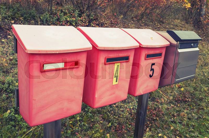 Old red post boxes on a roadside in a row, vintage tonal correction photo filter effect, stock photo