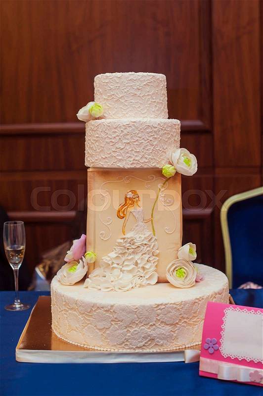 A multi level white wedding cake on a silver base and pink flowers on top , stock photo