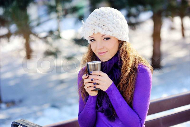 Portrait of the beautiful girl drinking hot beverage in snowy winter. , stock photo