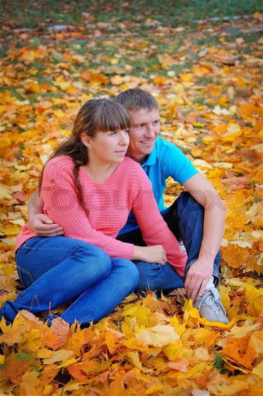Couple in love sitting on the autumn leaves, stock photo