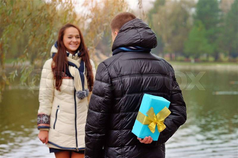 Back of a Japanese woman trying to pass a Christmas gift to man, stock photo