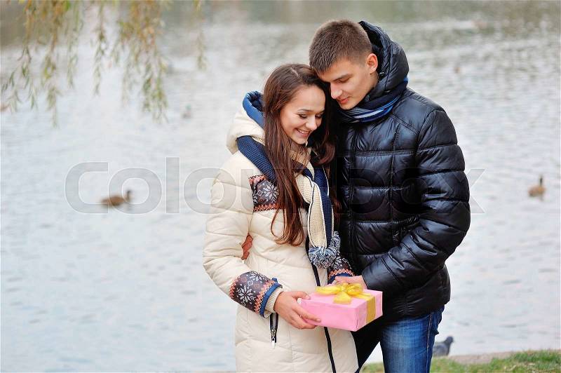 The young man gives a gift to a young girl in the cafe and they are kissing. , stock photo