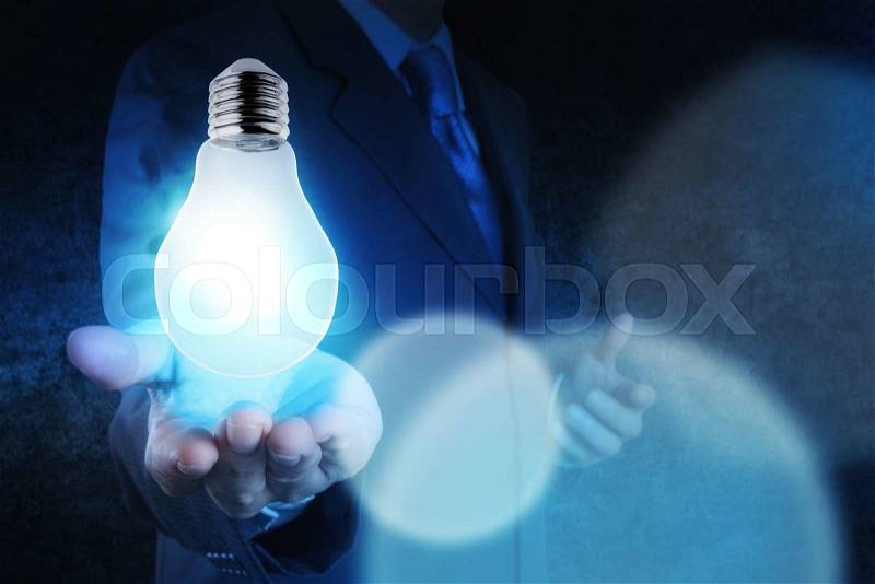 Light bulb in hand businessman on blue tone as concept, stock photo