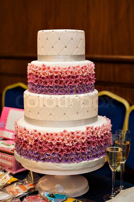 White multi level wedding cake with pink flower decorations, stock photo