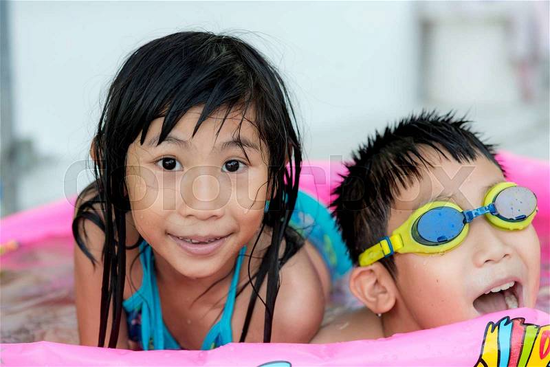 Cute happy children in goggles swimming in small pool, stock photo
