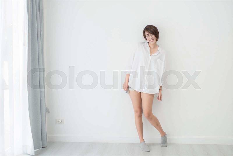 Attractive asian woman standing on floor with white wall, stock photo