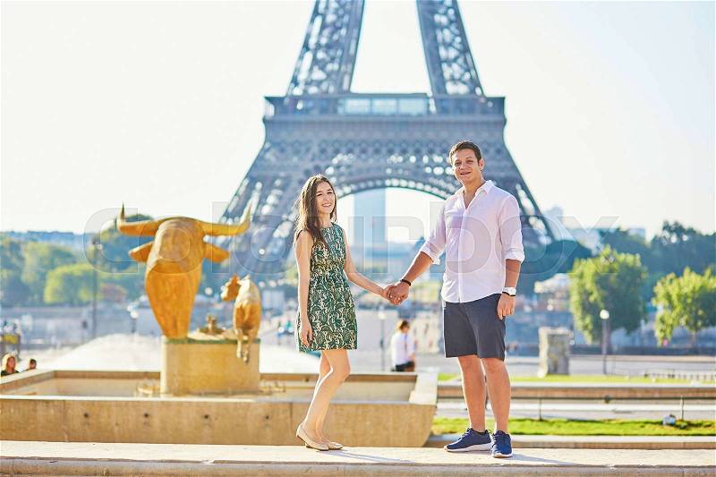 Young romantic couple in Paris near the Eiffel tower, enjoying their vacation to Paris, stock photo