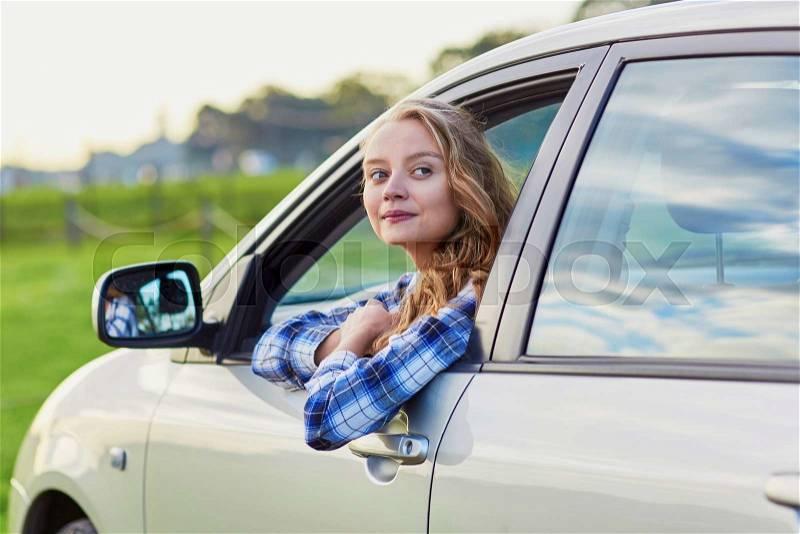 Beautiful young driver looking out of the car window, stock photo