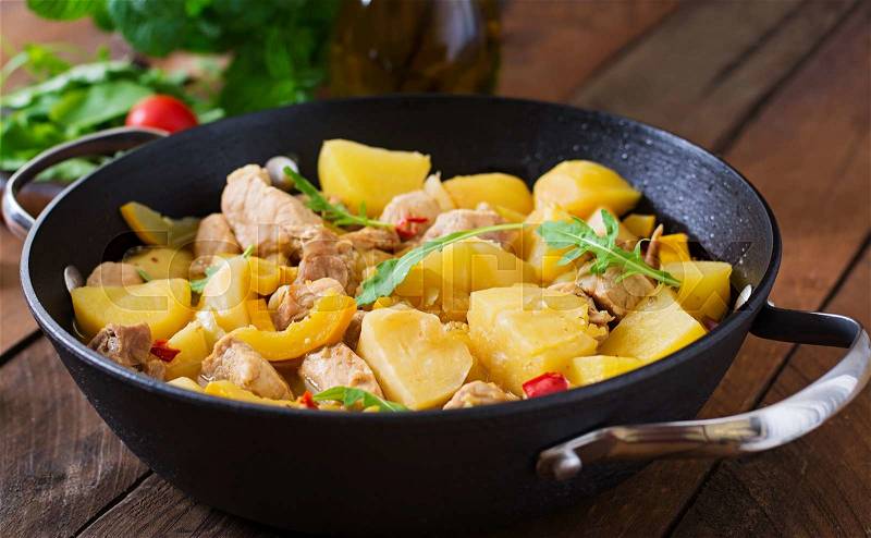 Stewed potatoes with meat and vegetables in a roasting tin on a wooden background, stock photo