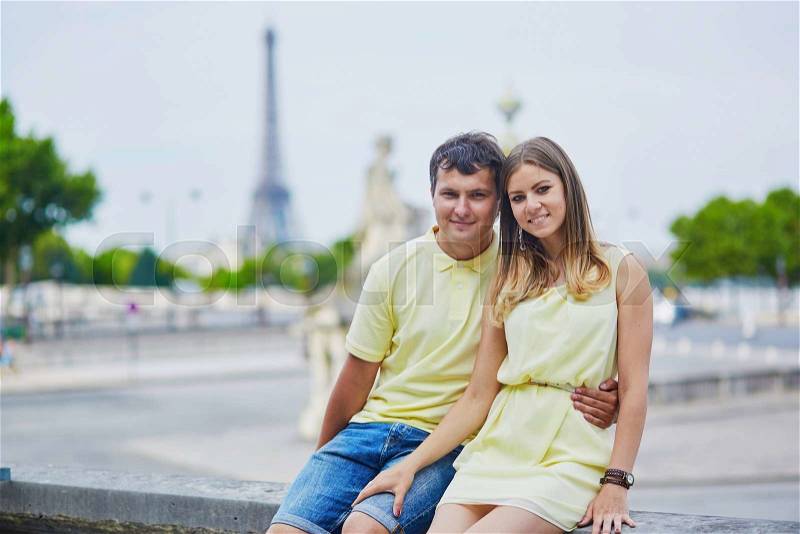 Beautiful young dating couple in Paris in the Tuileries garden, Eiffel tower in the background, stock photo