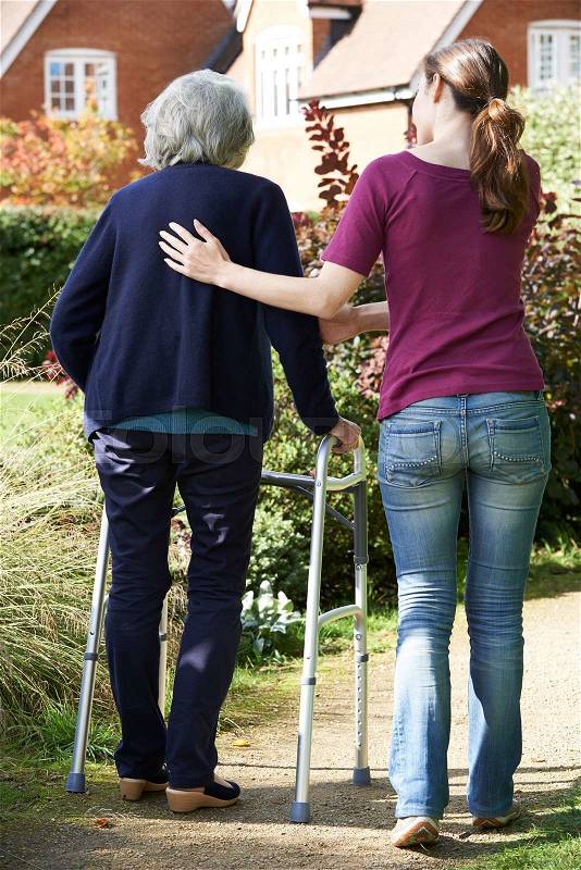 Daughter Helping Senior Mother To Use Walking Frame, stock photo
