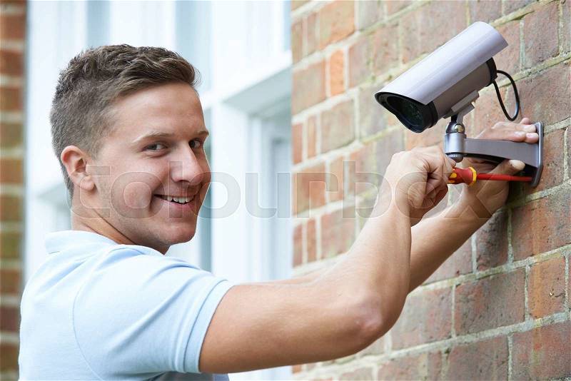Security Consultant Fitting Security Camera To House Wall, stock photo