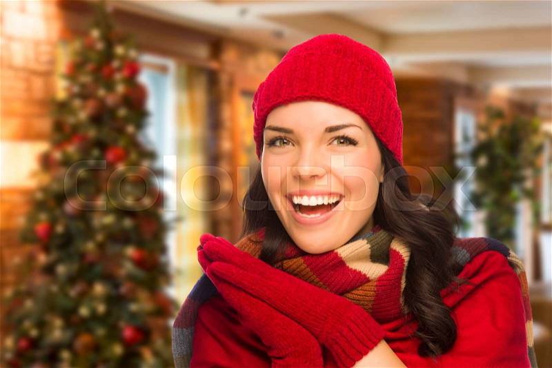 Happy Mixed Race Woman Wearing Mittens and Hat In Christmas Setting, stock photo