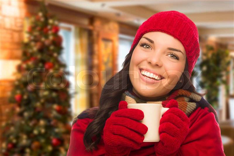 Warm Mixed Race Woman Wearing Winter Hat and Gloves In Christmas Setting, stock photo