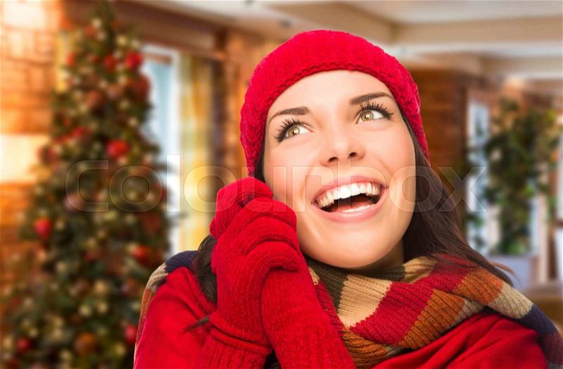 Happy Mixed Race Woman Wearing Mittens and Hat In Christmas Setting, stock photo