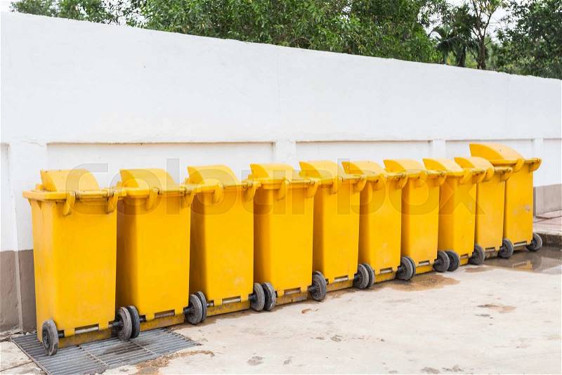 Row of yellow plastic garbage bin on the ground, stock photo