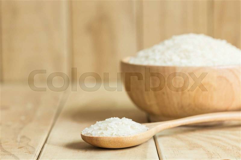 Close up Thai jasmine rice in wooden spoon on wooden background, stock photo