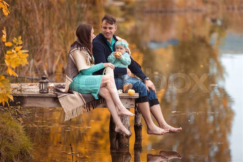 Young family resting on the lake shore, stock photo