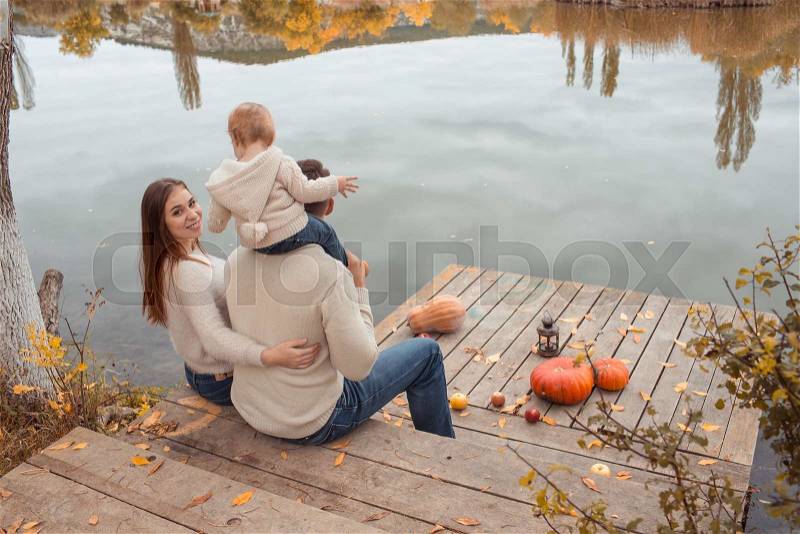 Young family resting on the lake shore, stock photo