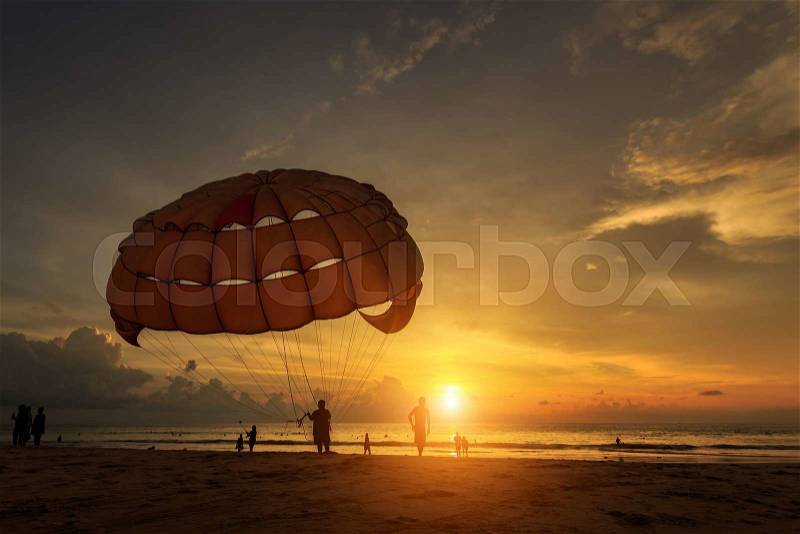 Silhouette of man is preparing para sailing at the sunset beach in Thailand, stock photo