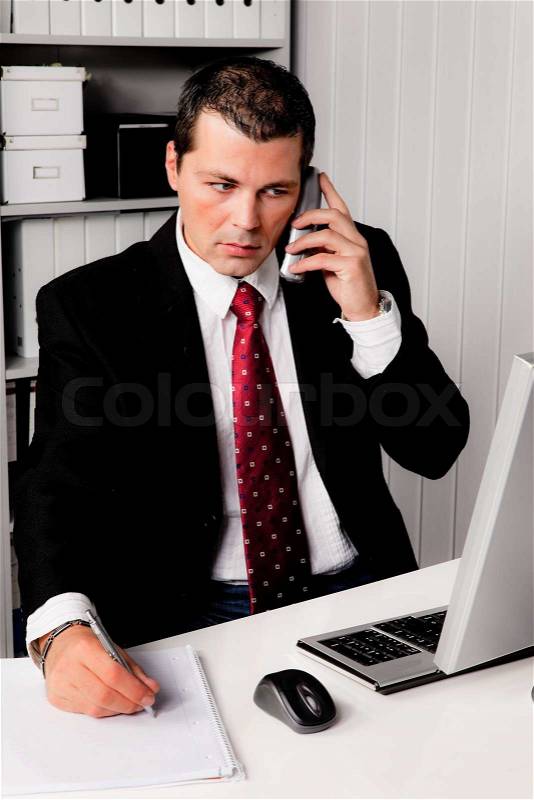 Young businessman in the office with a telephone. Seated at a desk, stock photo