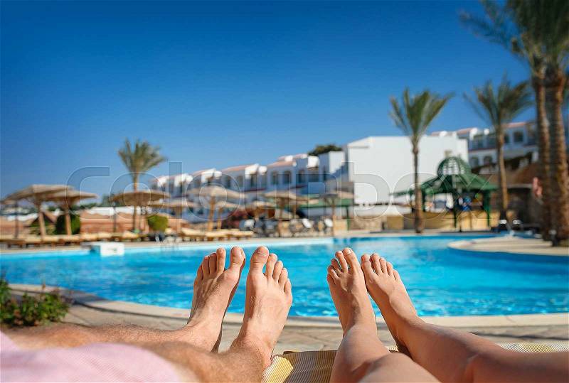 Feet resting on a background of the pool, stock photo