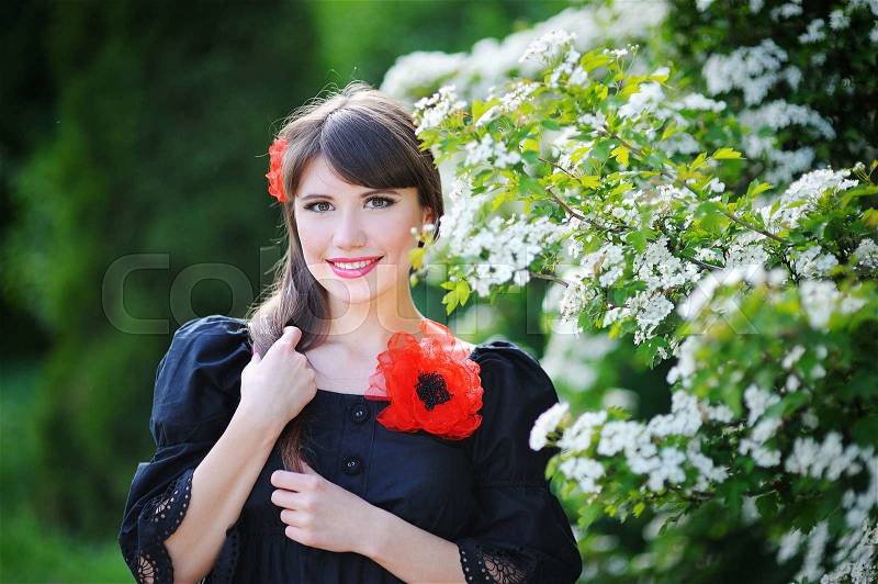 Girl with a red bow in the spring flowery park, stock photo