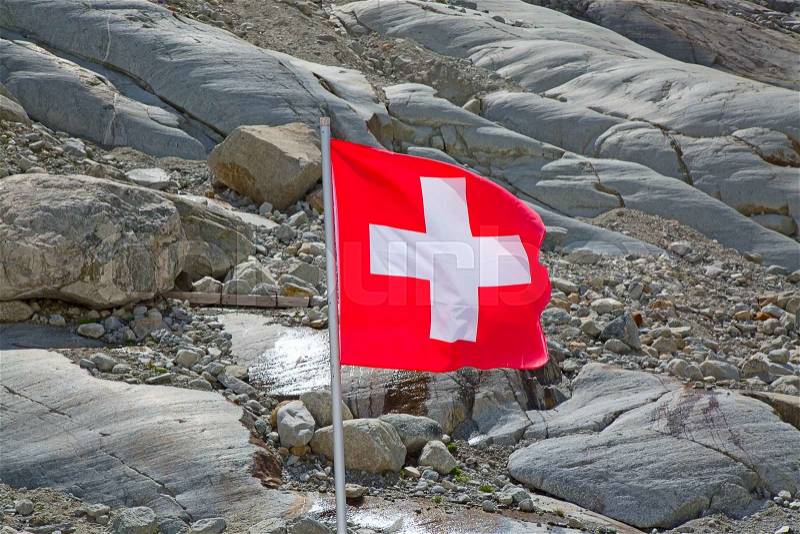 Swiss flag against rocky mountains, stock photo