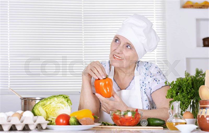 Portrait of a cute elderly woman preparing food, stock photo