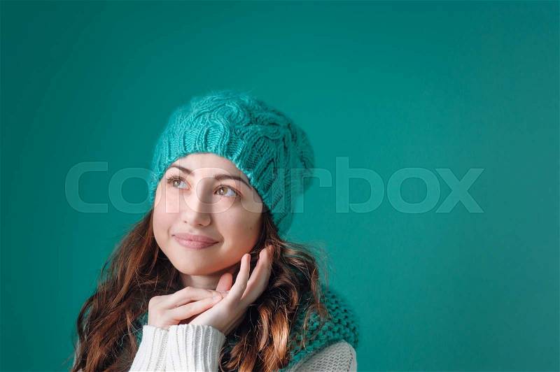 Young woman in knit scarf and hat dreams, stock photo