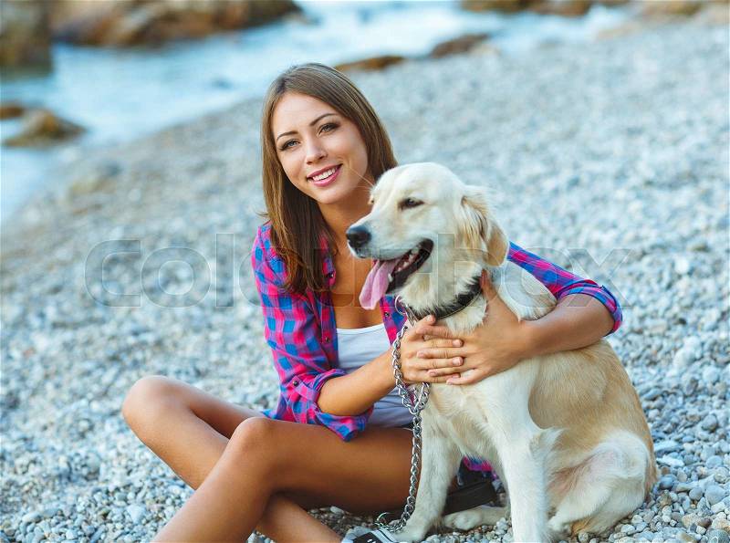 Summer vacation - woman with a dog on a walk on the beach, stock photo