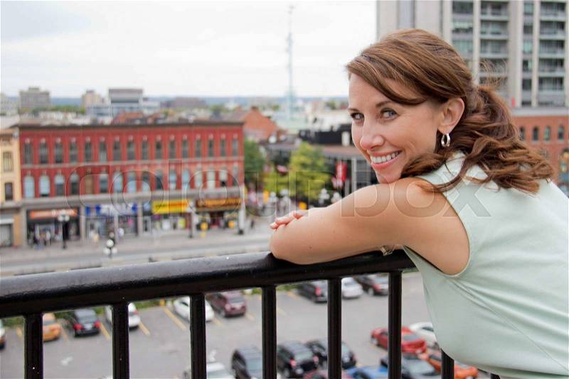 Smiling attractive young woman with city background looking at camera, stock photo