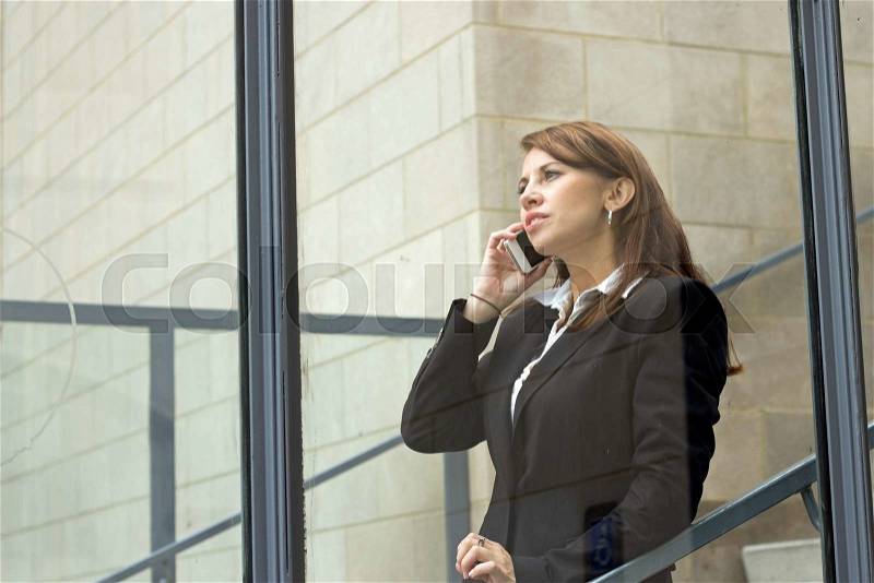 Window view of business woman talks on mobile cell phone, stock photo