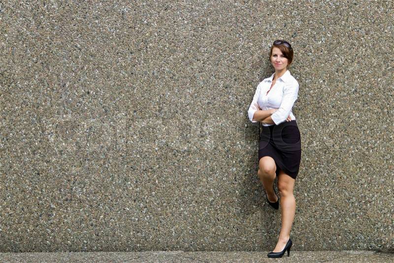 Attractive young business woman posing against grey wall - copy space, stock photo