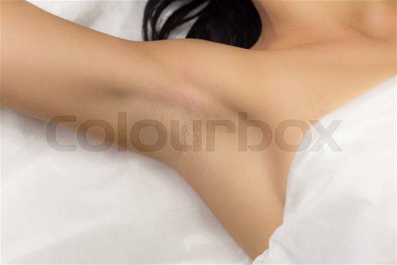 Underarm girl client after the procedure, laser hair removal in professional beauty studio. Client in white towel lies on the couch, stock photo