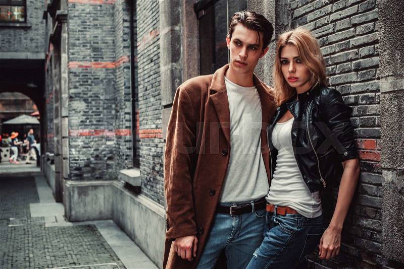 Young and trendy man and woman posing of the street with brick walls. Fashion style, stock photo