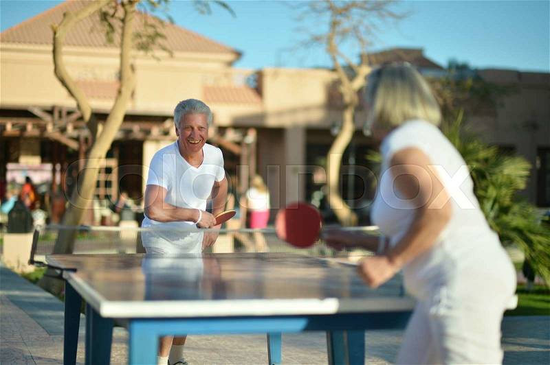 Elderly couple playing ping pong at hotel yard, stock photo