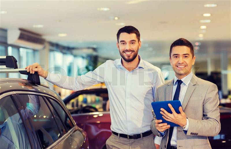 Auto business, car sale, techology and people concept - happy man and car dealer with tablet pc computer in auto show or salon, stock photo