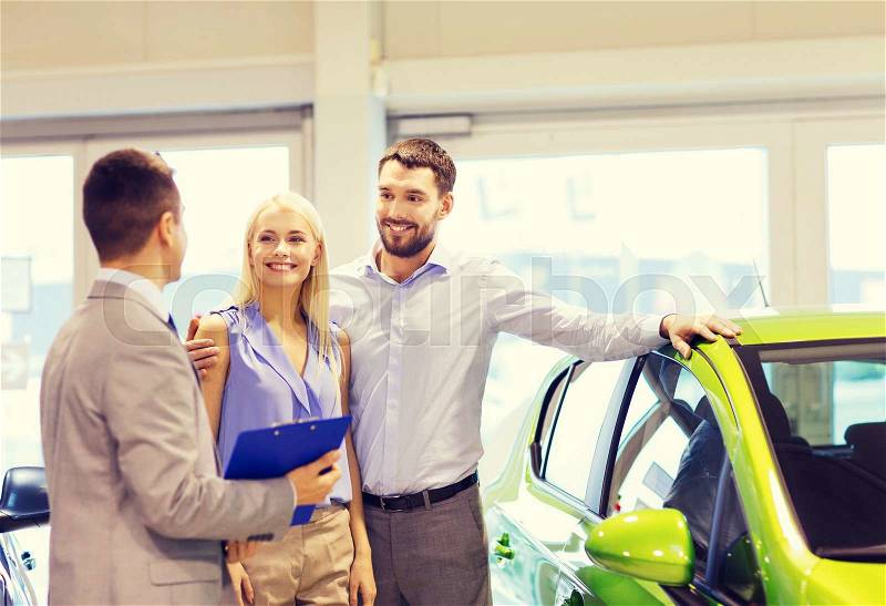 Auto business, car sale, technology and people concept - happy couple with car dealer in auto show or salon, stock photo