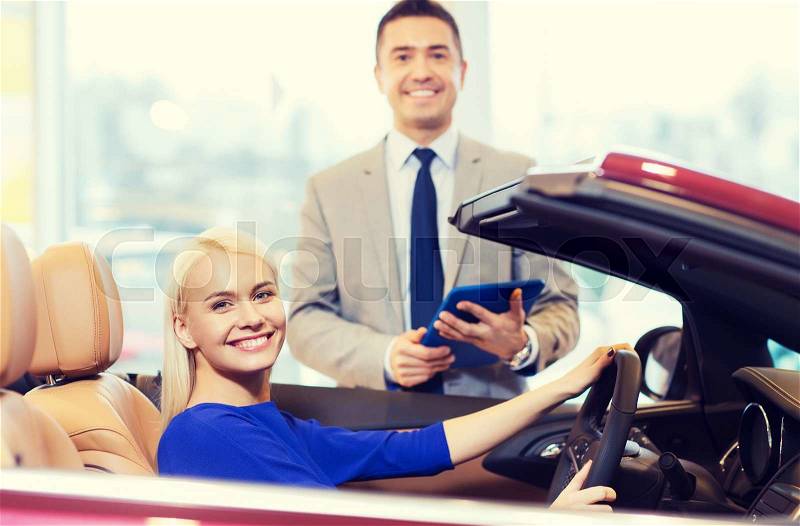 Auto business, car sale, technology and people concept - happy woman and car dealer with tablet pc computer in auto show or salon, stock photo