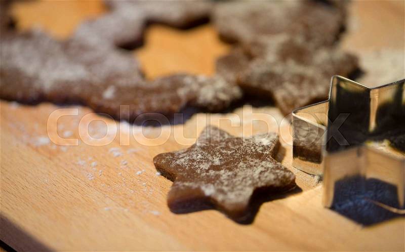 Baking, cooking, christmas and food concept - close up of gingerbread dough, molds and flour on wooden cutting board from top, stock photo