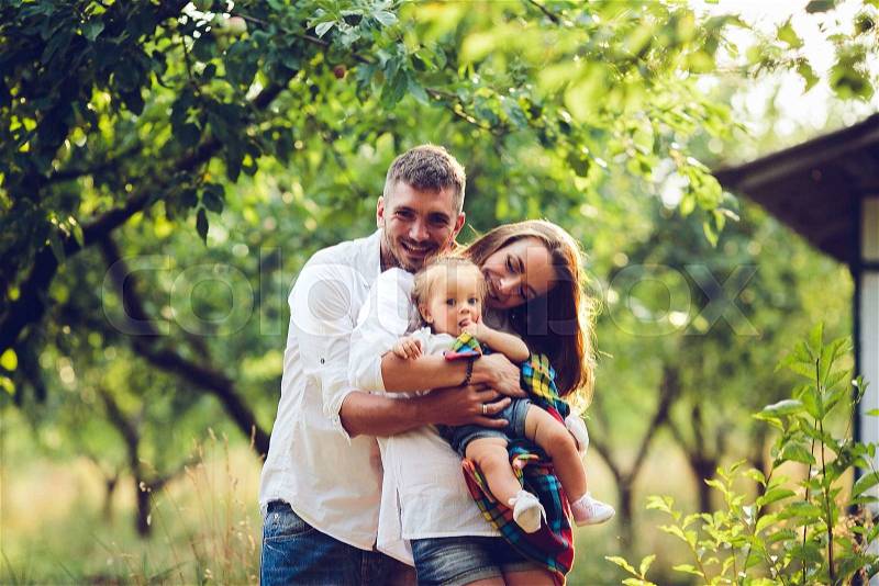 Dad, mom and little girl on the farm on a background of trees, stock photo
