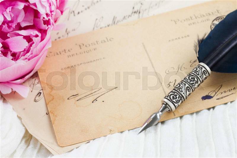 Pink peony flower with antique blank letter with copy space and feather pen on white lace background, stock photo