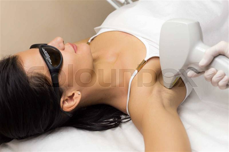Laser hair removal in professional beauty studio. Beautician in white sterile gloves make the procedure on the client\'s armpit, stock photo