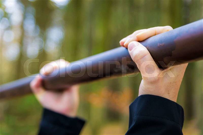 Closeup of hands on a fitness bar outdoor in forest with free space, stock photo
