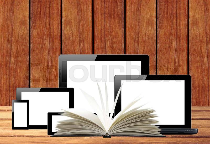 Tablet pc, mobile phone, computer and openned book on wooden table, stock photo
