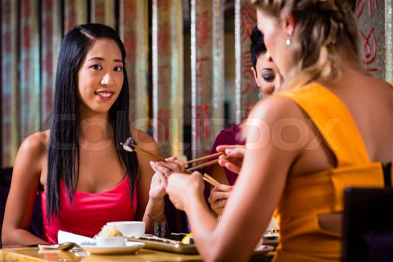 Young people eating sushi in Asian restaurant, stock photo