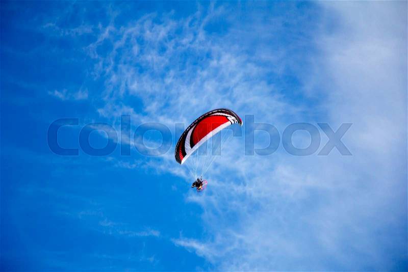 Paraglider with motor flies in the blue sky , stock photo