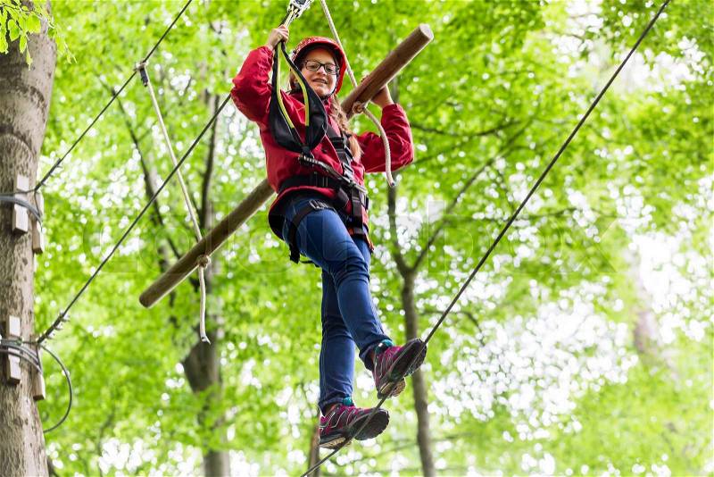 Child reaching platform climbing in high rope course, stock photo